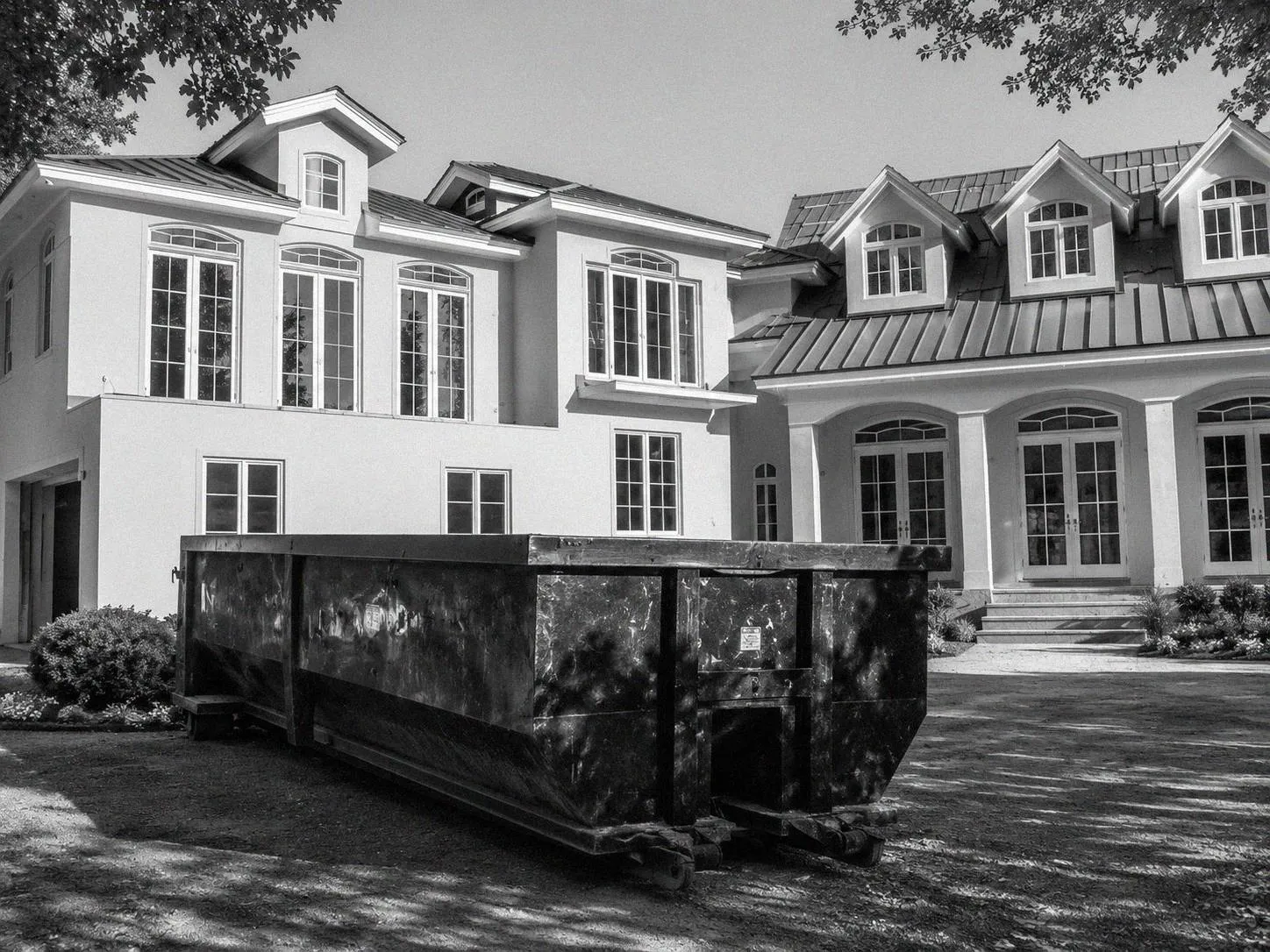 Roll-off dumpster in a driveway in front of a home